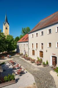 a large white building with a church in the background at Stanglbräu in Hausen