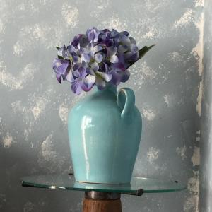 un jarrón azul lleno de flores púrpuras en una mesa en casa Radegonda, en Sornico