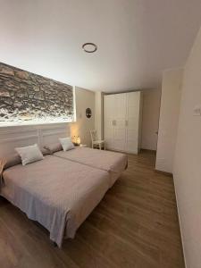 a bedroom with a large bed and a stone wall at Apartamentos Rurales Sariar in Villar
