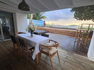 a table and chairs on a deck with a view of the ocean at Le joyau de Pinel in Saint Martin
