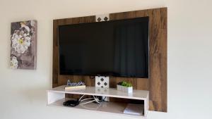 a flat screen tv on a wall with a white shelf at Apartamento Aconchego da Serra Azul in Barra do Garças