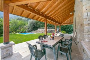 a patio with a table and chairs under a wooden pergola at Villa Louise in San Siro