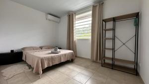 a bedroom with a bed with a table and a window at Vista - Route des plages - Destination Guyane in Rémire-Camp