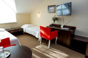 a hotel room with two beds and a desk and a television at Hotel Alexandra in Pobiedziska