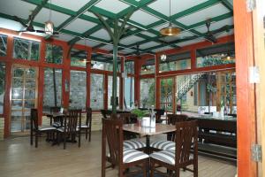 a dining room with tables and chairs and windows at Hotel YAN Residency Bhimtal - Nainital in Bhīm Tāl