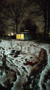 a snow covered yard at night with a building in the background at Studio Zebra in Heikant