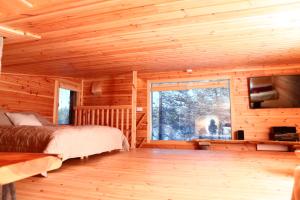 a bedroom of a log cabin with a bed and a window at Rahkis Lodge Saariselkä in Saariselka