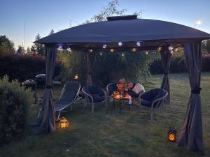 a woman sitting under a gazebo in a yard at Zuzanna in Storebro +8 photos
