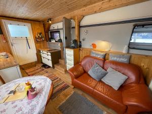 a living room with a leather couch and a kitchen at Tiny House Anneliese, Klimaanlage, E-Bikes, Hunde ok in Oberbettingen