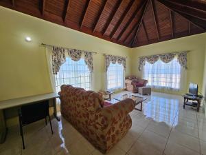 a living room with a couch and some windows at Quiet Escape Unity Hall in Montego Bay