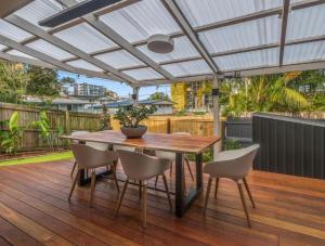 a patio with a wooden table and chairs on a deck at The Mooloolaba Gallery in Mooloolaba