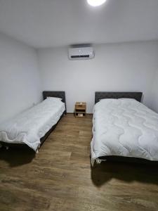 a bedroom with two beds and a tv on the wall at Montana apartman in Han Pijesak