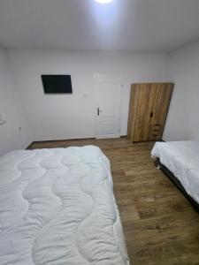 a white room with a large bed and a tv at Montana apartman in Han Pijesak +3 photos