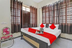 a bedroom with a bed with red pillows and a chair at Hotel O by OYO Sunrise Inn in Gorakhpur