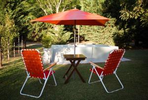 two chairs and a table with a red umbrella at Cerveceria BEERDIER Alojamiento in Salto
