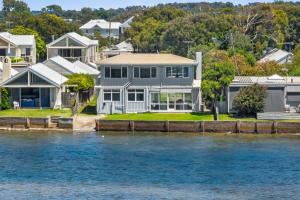 a house on the shore of a body of water at River Meets Ocean Edge - Absolute Waterfront in Barwon Heads