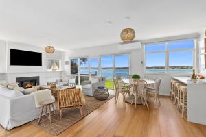 a living room with white furniture and a view of the ocean at River Meets Ocean Edge - Absolute Waterfront in Barwon Heads