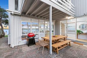 a patio with a wooden table and chairs and a grill at River Meets Ocean Edge - Absolute Waterfront in Barwon Heads