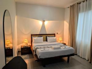 a bedroom with a bed with two lamps and a mirror at Hakuna Matata, 3 min to Speke Resort, Opposite Caramel, Munyonyo in Kampala