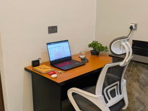 a laptop computer sitting on a wooden desk with a chair at Hakuna Matata, 3 min to Speke Resort, Opposite Caramel, Munyonyo in Kampala