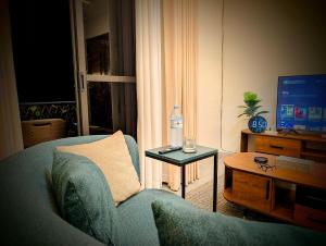 a living room with a couch and a table with a water bottle at Hakuna Matata, 3 min to Speke Resort, Opposite Caramel, Munyonyo in Kampala