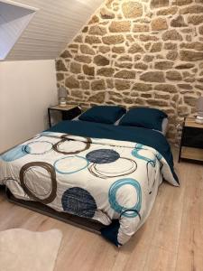 a bed in a bedroom with a stone wall at Maison en pierre pour 6-jardin &animaux bienvenus in Languidic