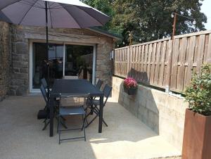 a table and chairs with an umbrella on a patio at Maison en pierre pour 6-jardin &animaux bienvenus in Languidic