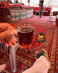 a person holding a glass of beer on a table at MARS MIRROR BUBBLE lUXURY CAMP in Wadi Rum +37 photos