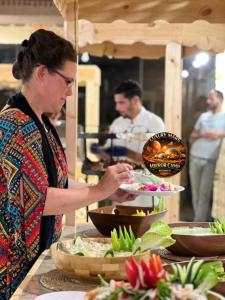 a woman standing in a kitchen preparing food at MARS MIRROR BUBBLE lUXURY CAMP in Wadi Rum