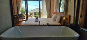 eine Badewanne in einem Schlafzimmer mit einem Bett in der Unterkunft Villa Trident Srithanu Koh Phangan 2 min of Zen Beach in Ko Kong Nui