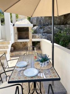 a table with plates and an umbrella on a patio at House Sea la vie in Murter