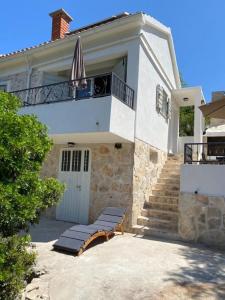 a white house with a bench and an umbrella at House Sea la vie in Murter