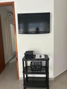 a flat screen tv hanging on a wall with a table at Apartamento do Peró in Cabo Frio