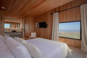 a bedroom with a white bed and a large window at Locus Solus Hotel Singular in Mar del Plata