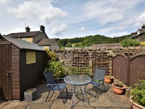a patio with a table and chairs and a stone wall at 2 Bed in Eyam oc-pk812 in Eyam