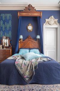 a blue bedroom with a bed with a wooden head board at Maison d'Artiste in Ghent