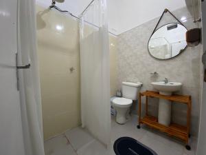a bathroom with a toilet and a sink and a mirror at Cantinho do Viajante in Arraial do Cabo
