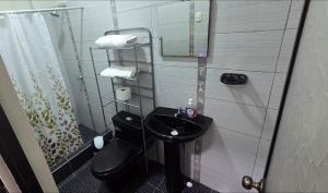 a bathroom with a black toilet and a sink at Ximena's House in Iquitos