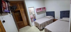 a small room with two beds and a television at Ximena's House in Iquitos +6 photos