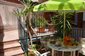 un balcón con una mesa con plantas y una sombrilla en B&B Vicolo del Chiostro, en Aci SantʼAntonio