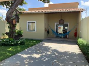 a house with a hammock outside of it at Casa dos cajueiros in Paracuru