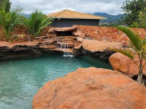 a waterfall in a pool of water with rocks at Aromas&Brumas Pousada in Brumadinho
