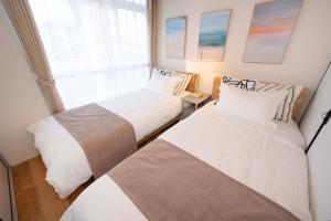 two beds in a small room with a window at KURIHAMA Base 102 in Kubiri