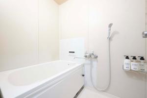 a white bathroom with a shower and a tub at KURIHAMA Base 102 in Kubiri