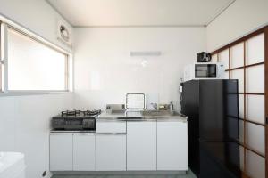 a kitchen with white cabinets and a black refrigerator at KURIHAMA Base 102 in Kubiri +22 photos