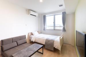 a bedroom with a bed and a couch and a tv at コート エトワレ マエザト-新築アパートメントホテル- in Ishigaki Island