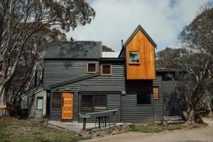 a black house with a wooden roof at Dibbin’s Chalet in Dinner Plain