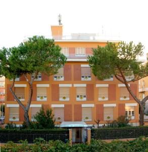 un bâtiment oranger avec des arbres devant lui dans l'établissement La Casa di Nazareth, à Rome