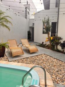 a patio with two chairs and a swimming pool at Pousada Vivenza - Suíte 03 e 04 in Laguna