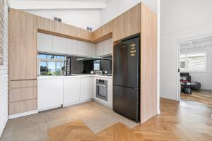 a kitchen with white cabinets and a black refrigerator at Apollo Bay Gone Surfin in Apollo Bay